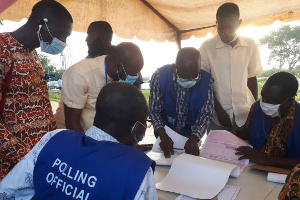 Polling station offcials cross-check names of special voters