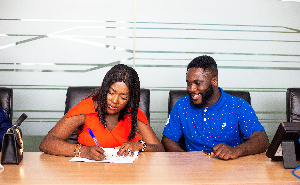 A photo of Fella Makafui signing her deal with Glover