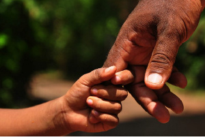 File photo of the hands of a father and son. Credit: Brett Davies