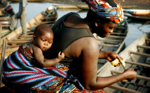 A working mother wraps her child at her back