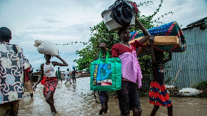 Displaced people in central South Sudan walk with their belongings in a flooded area