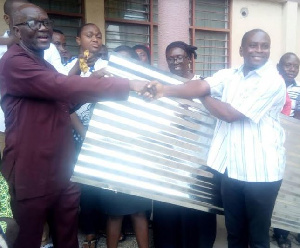 MP for Yilo Krobo, Lawyer Magnus Kofi Amoatey presenting the roofing sheets to  Mr. Joseph Atta-Baah