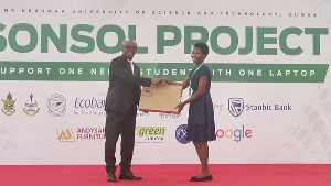 Stephen Amoah presenting laptop to a brilliant student